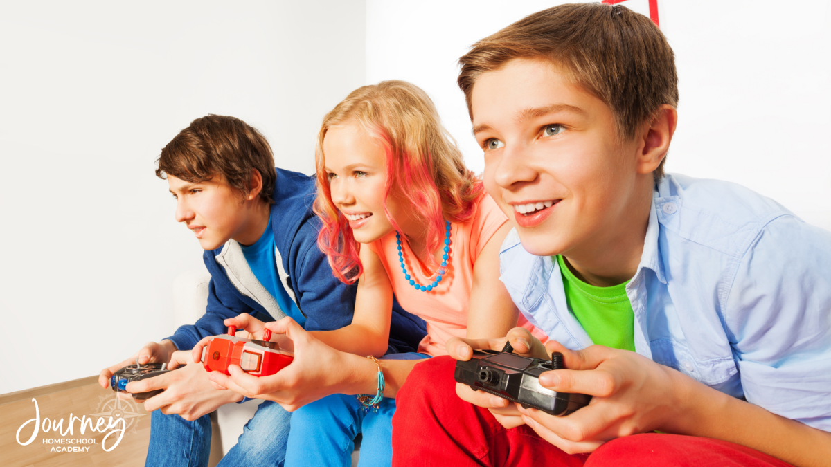 Three homeschool students smiling while playing video games, illustrating STEM learning opportunities with Journey Homeschool Academy.