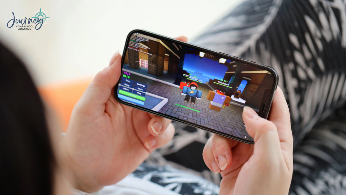 Close-up of a student playing Roblox on a smartphone, connecting coding and game design with homeschool STEM science at Journey Homeschool Academy.